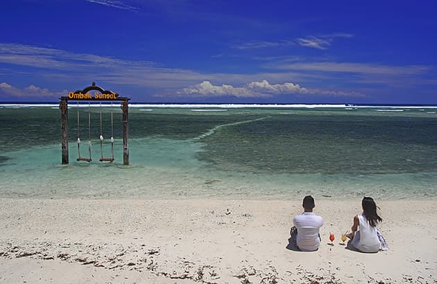 A couple sitting on a beach drinking cocktails