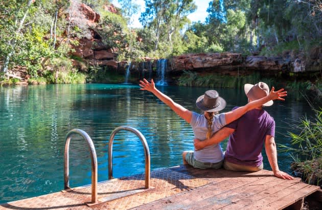 Couple sitting on edge of Fern Pool in Karijini National Park