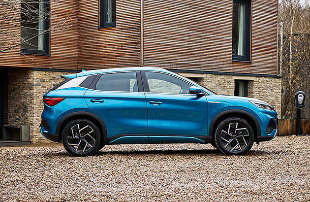 A blue BYD Atto 3 parked outside a home in the countryside