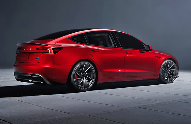 A red Tesla Model 3 in a dark studio set
