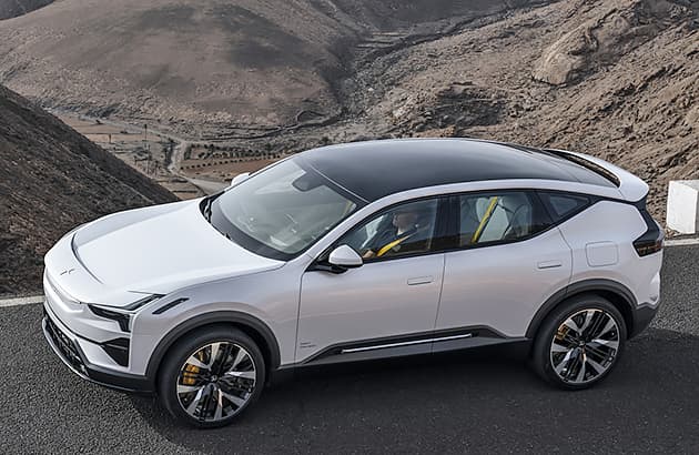 A white Polestar 2 parked on a road in mountainous landscape