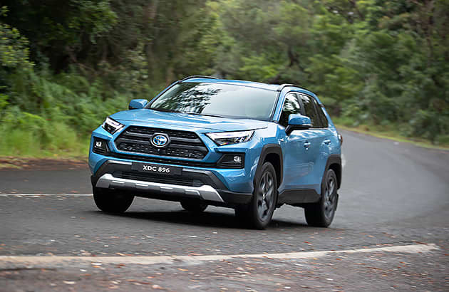 A blue Toyota RAV4 driving on a country road