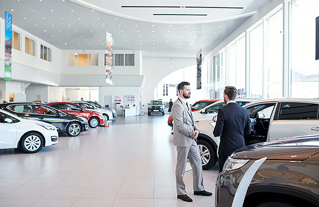 Two men speaking inside a car showroom