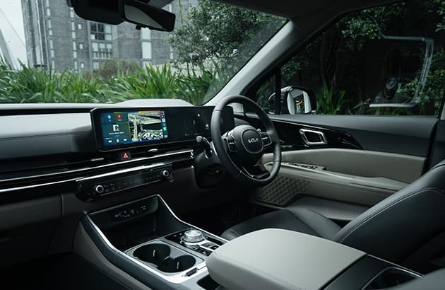 A Kia Carnival interior showing the dashboard, steering wheel and infotainment screen
