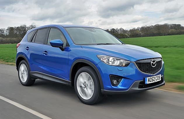 A blue Mazda CX-5 driving on a country road.
