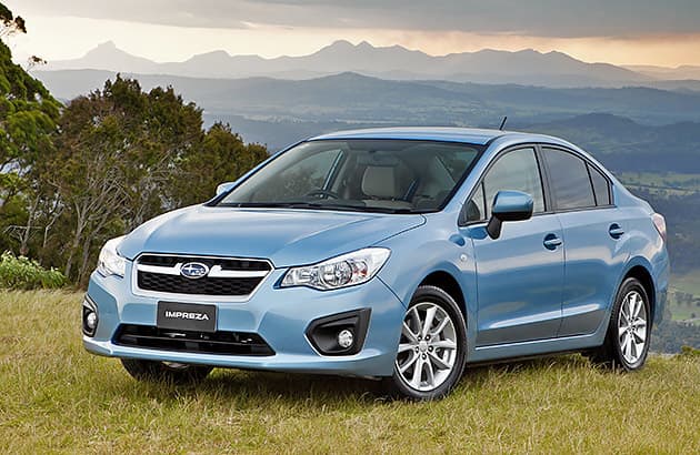 A light blue Subaru Impreza parked on a grassed hillside.
