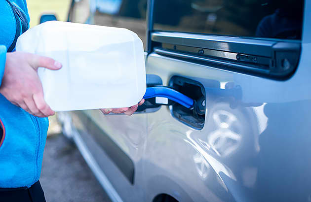 A person pouring AdBlue into a car's AdBlue tank from a bottle