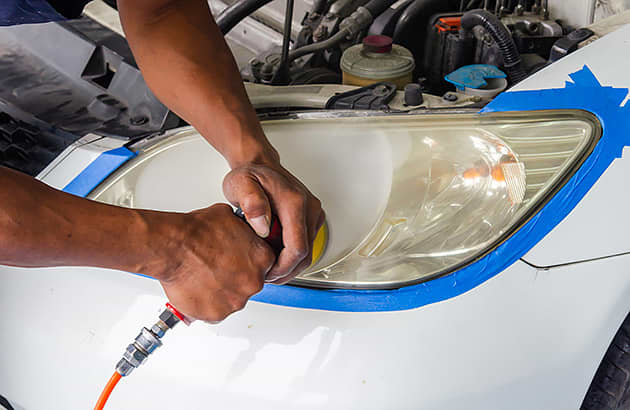 A close-up of someone polishing a car headlight