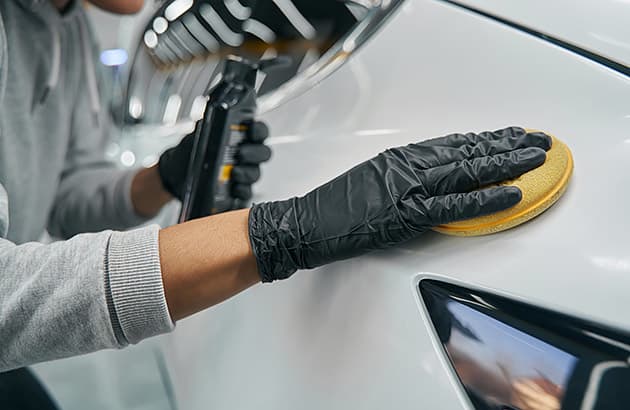 A close-up of someone polishing a car bonnet