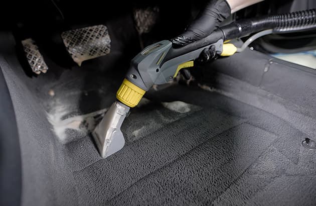 A close-up of someone vacuuming a car floor