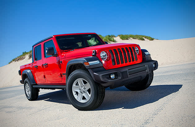 A red Jeep Gladiator parked on a white sand dune against a blue sky