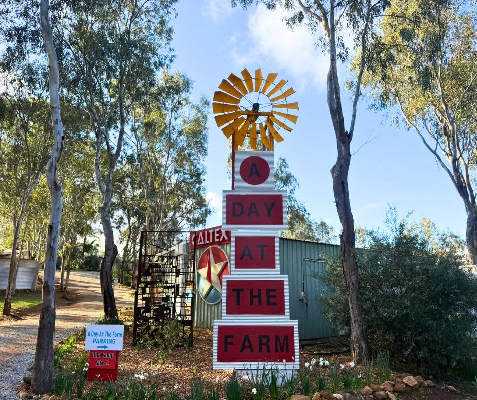 Entry sign reading "A Day at the Farm" with windmill and shed amongst trees