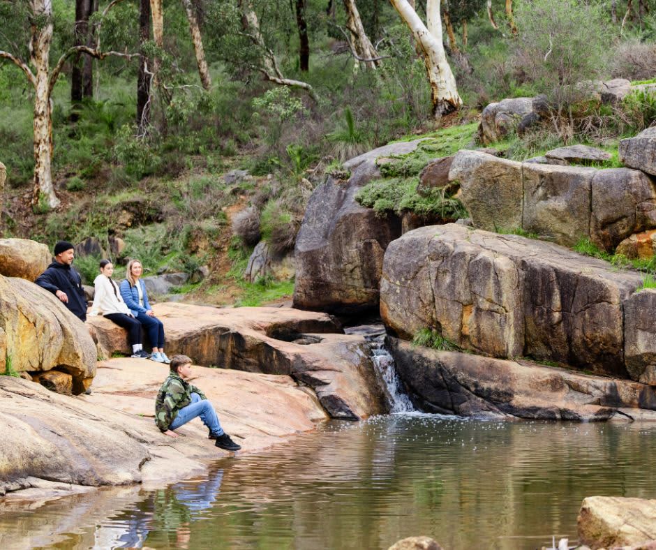 Group of people sitting by the rocks in winter clothing admiring the views