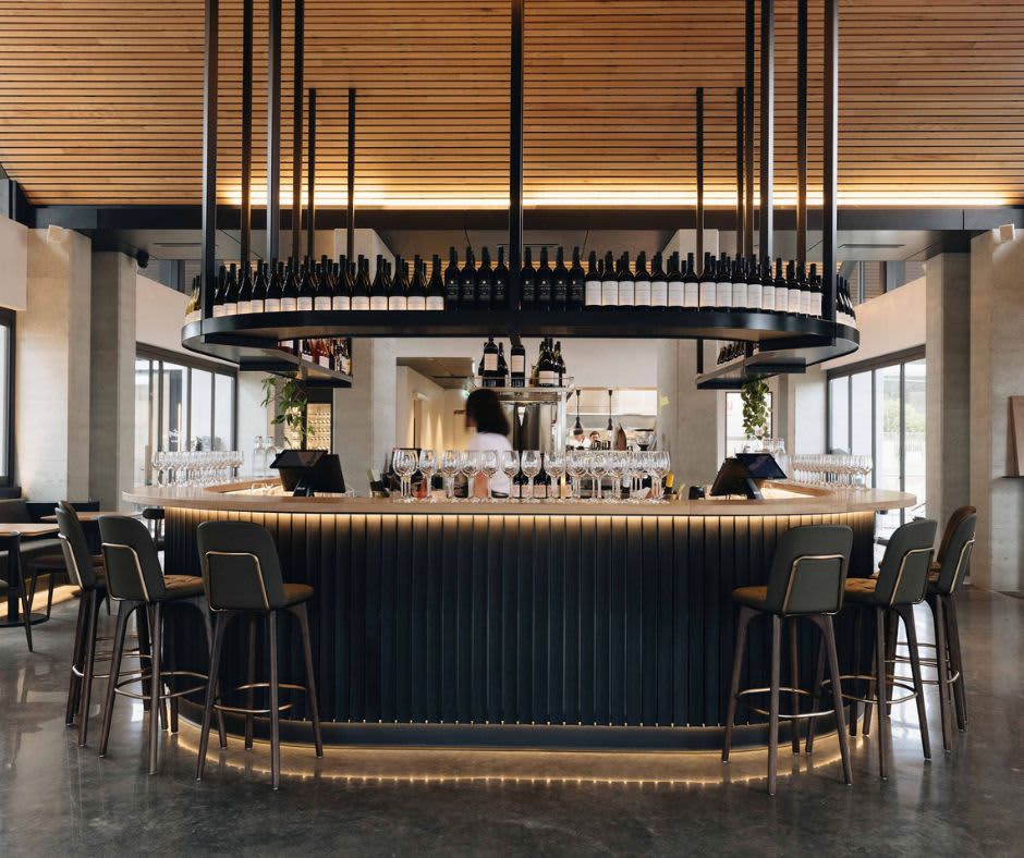 Circular bar with wine glasses lined up and bar stools and natural lighting