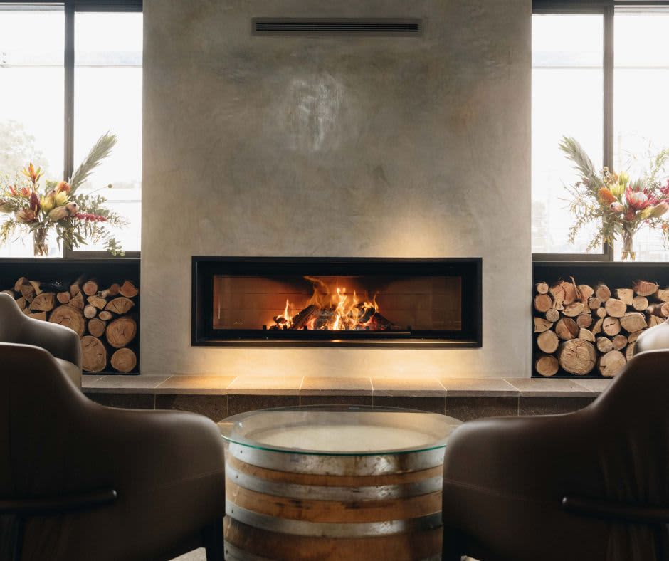 Two cosy chairs with a wine barrel and large fireplace