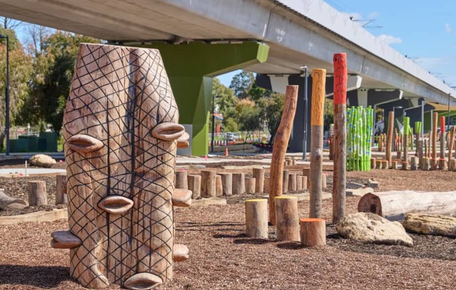 Sculpture artwork and nature play underneath elevated rail line