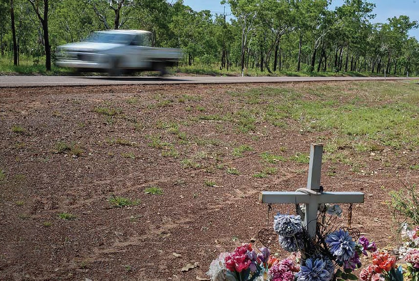 A white cross in the gravel on the side of country road