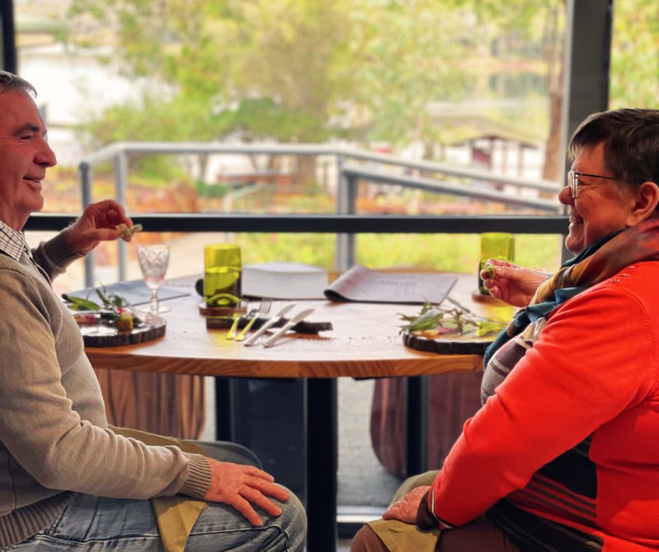 Two guests seated at table overlooking Lake enjoying degustation dining experience