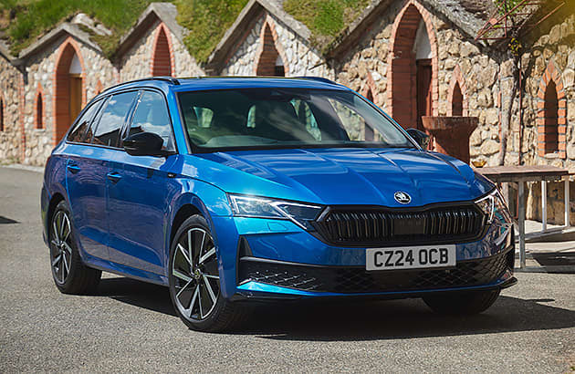 A blue Skoda Octavia parked near an old stone building.