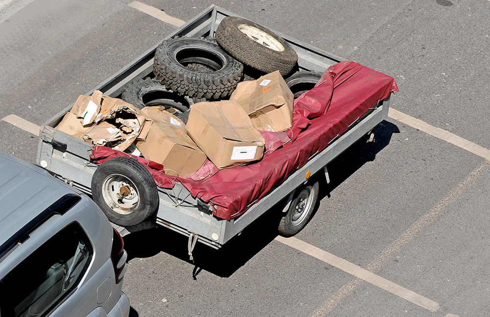 A trailer loaded with lose junk including old tyres and boxes