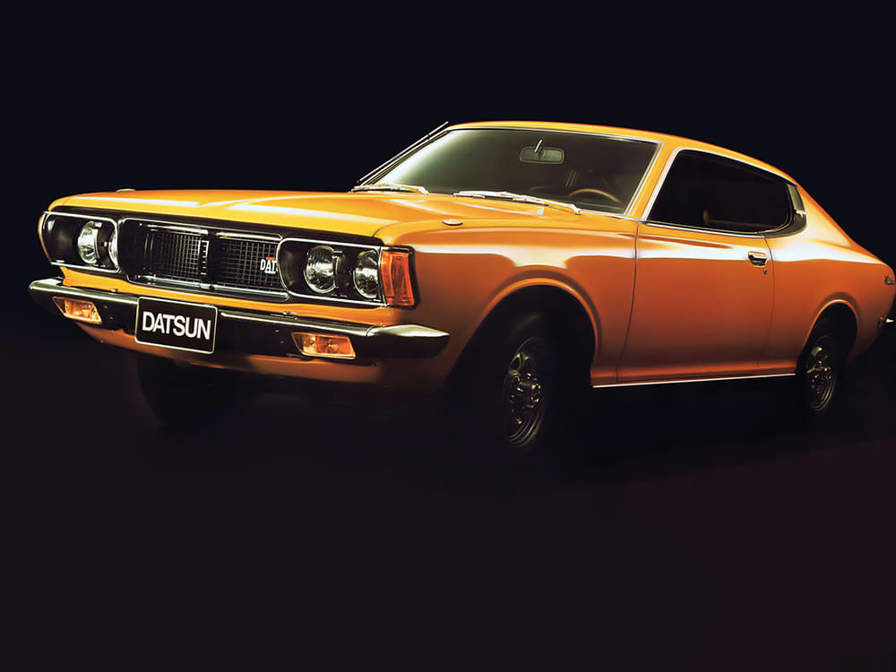 An orange Datsun 180B in a dark studio setting