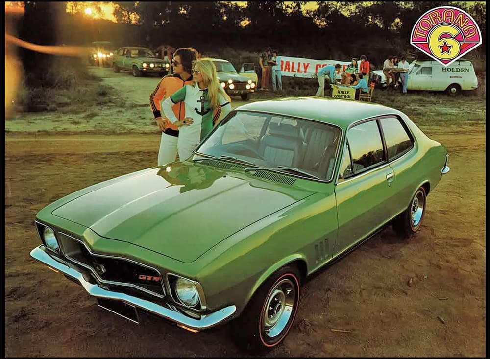 A green Holden Torana GTR at a car show with a man and woman standing next to the driver's side, 1970s vintage