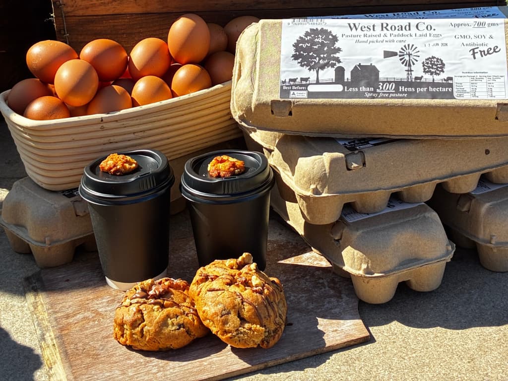 An eye-level shot shows a rustic food display featuring farm-fresh eggs, coffee, and cookies on a wooden surface.