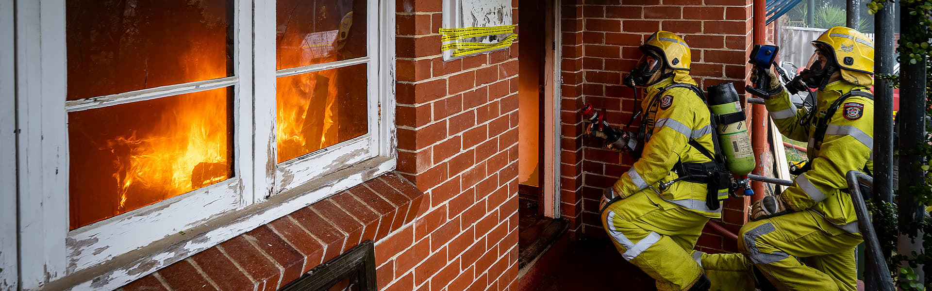 Two fire fighters spraying water into a home from the front door