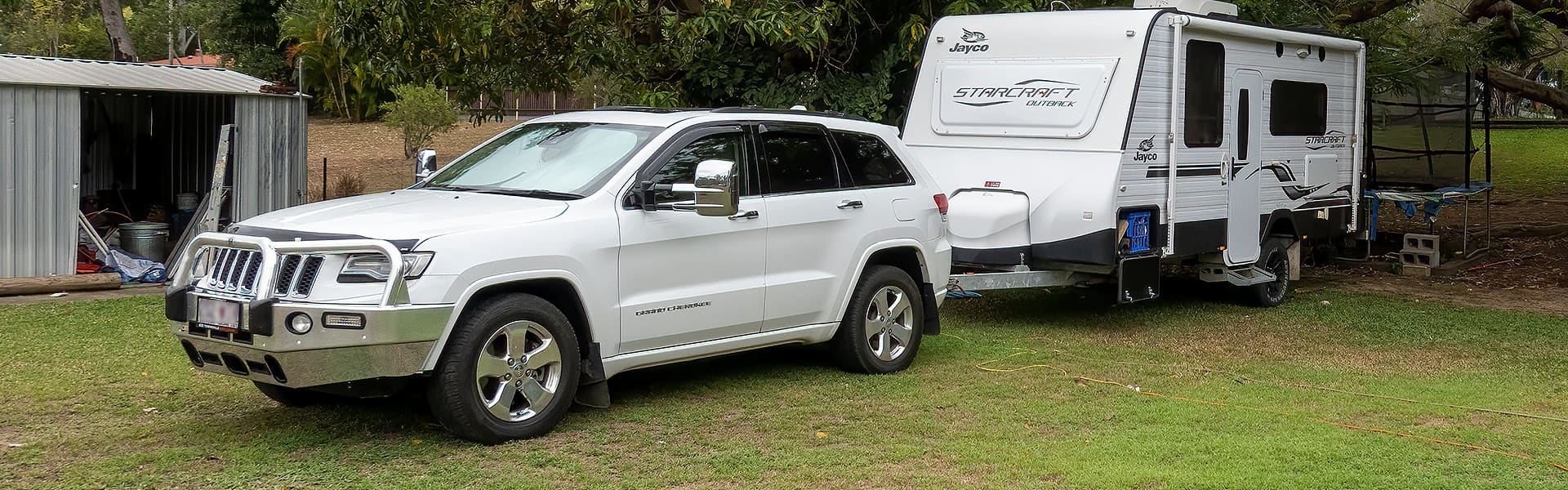 A caravan hitched to  white four-wheel drive in the yard of a home