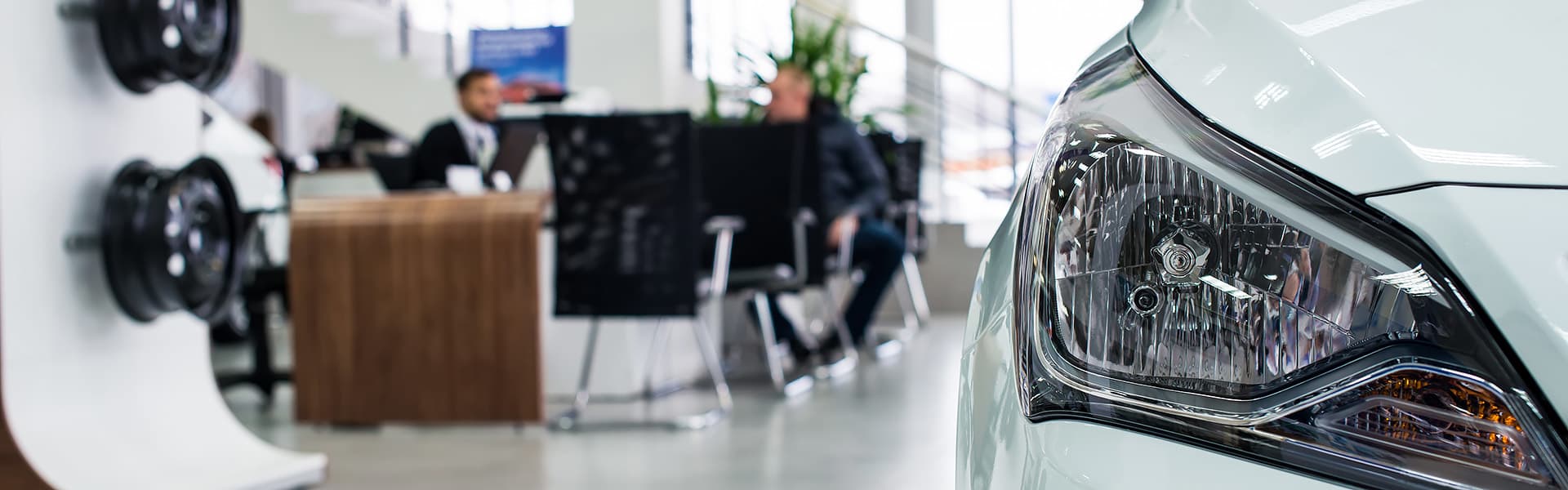 Two people at a desk in car dealership showroom