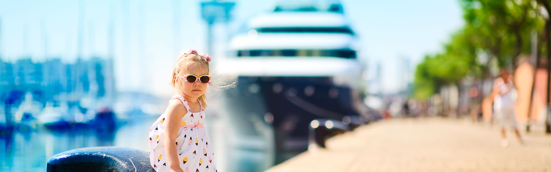 A young girl standing in front of a cruise ship in port