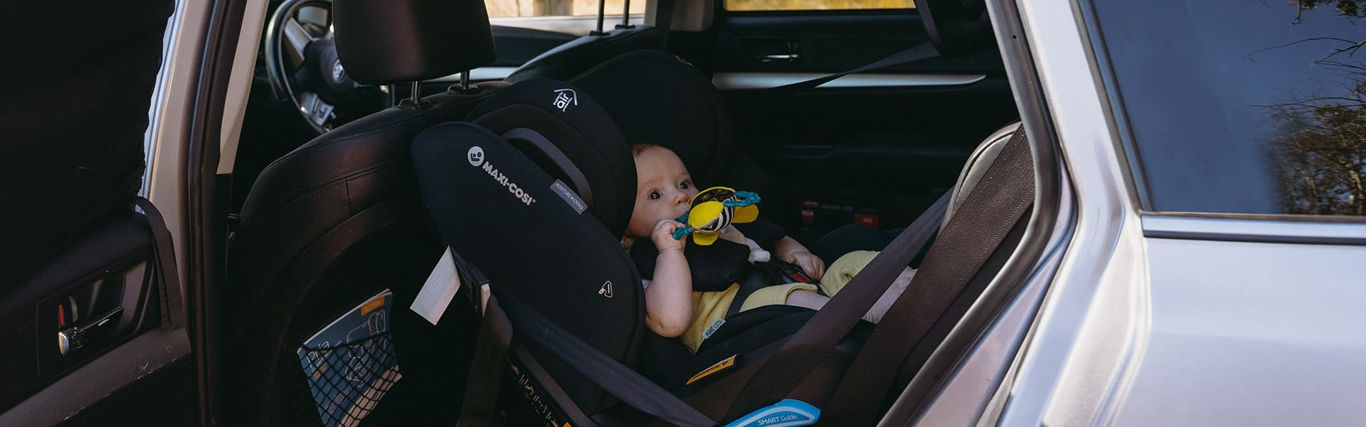 A baby seat installed in a car with a child seated in position