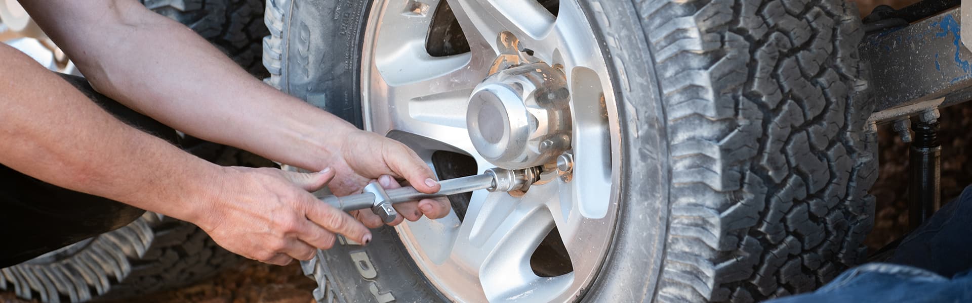 A pair of hands shown removing the nuts on a caravan wheel in order to change the tyre