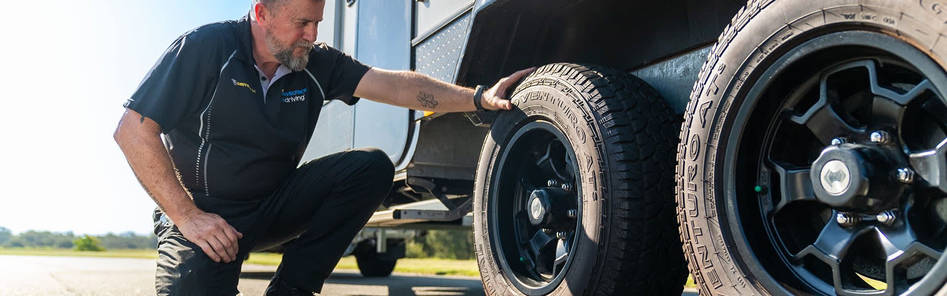 Man kneeling down beside caravan looking at the tyre