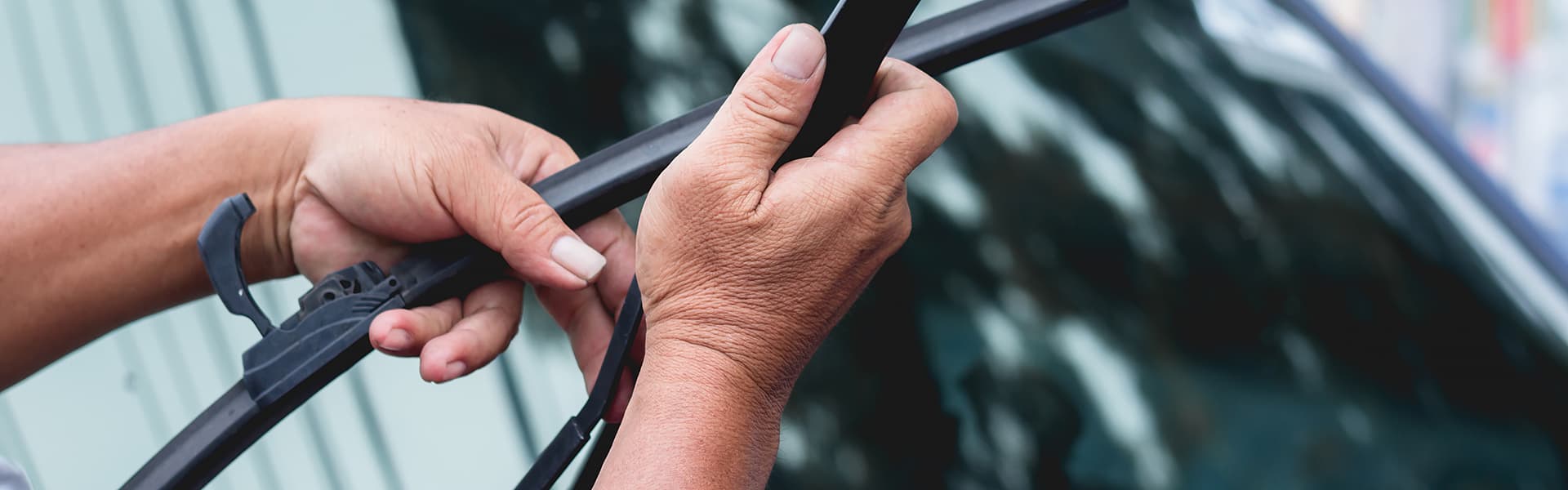 A person is clipping a wiper blade on a windscreen wiper arm