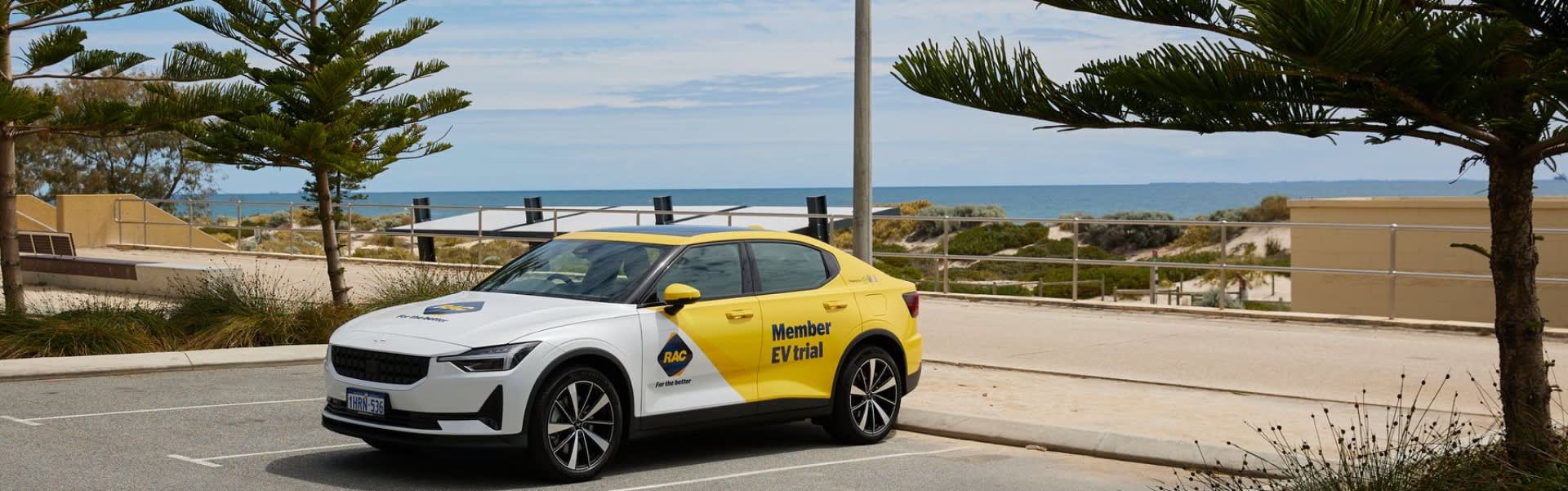 Yellow RAC branded Polestar 2 electric car parked in front of beach