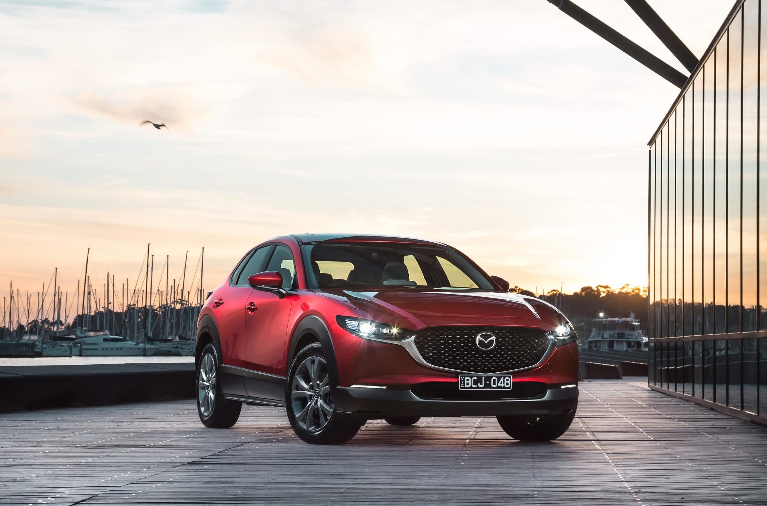 Red Mazda CX30 in front of boat harbour at sunset