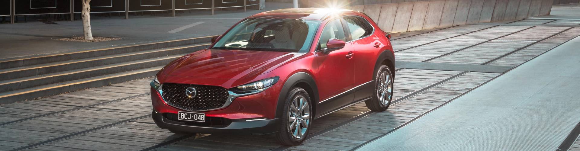 Red Mazda CX-30 driving in urban setting