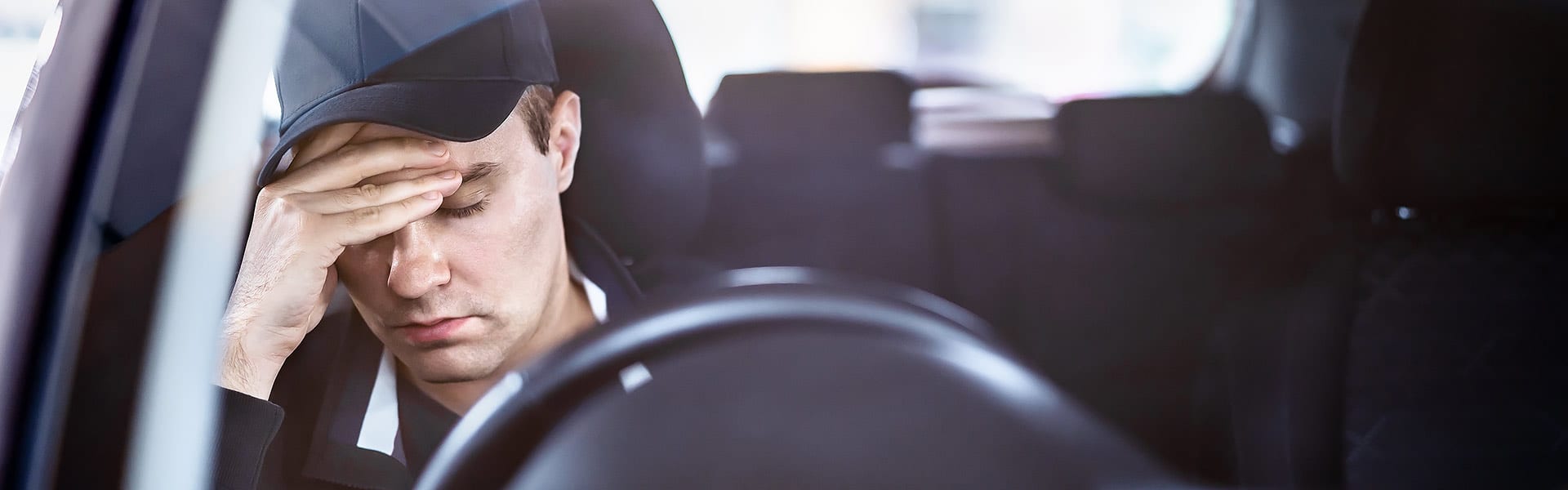 A young male driver with his head resting on one of his hands