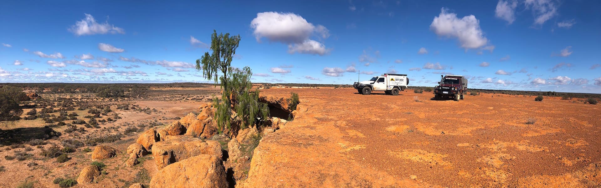 Two four-wheel drives on a high rock plateau overlooking a rocky dry landscape
