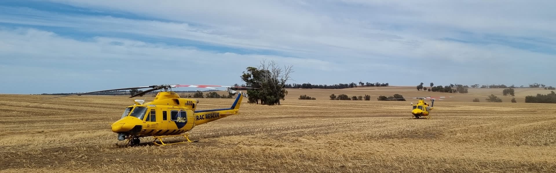 Two RAC Rescue helicopters landing on field