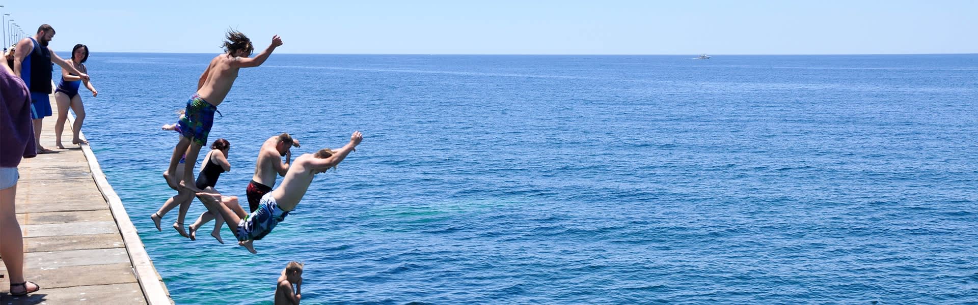 People jumping off a jetty.