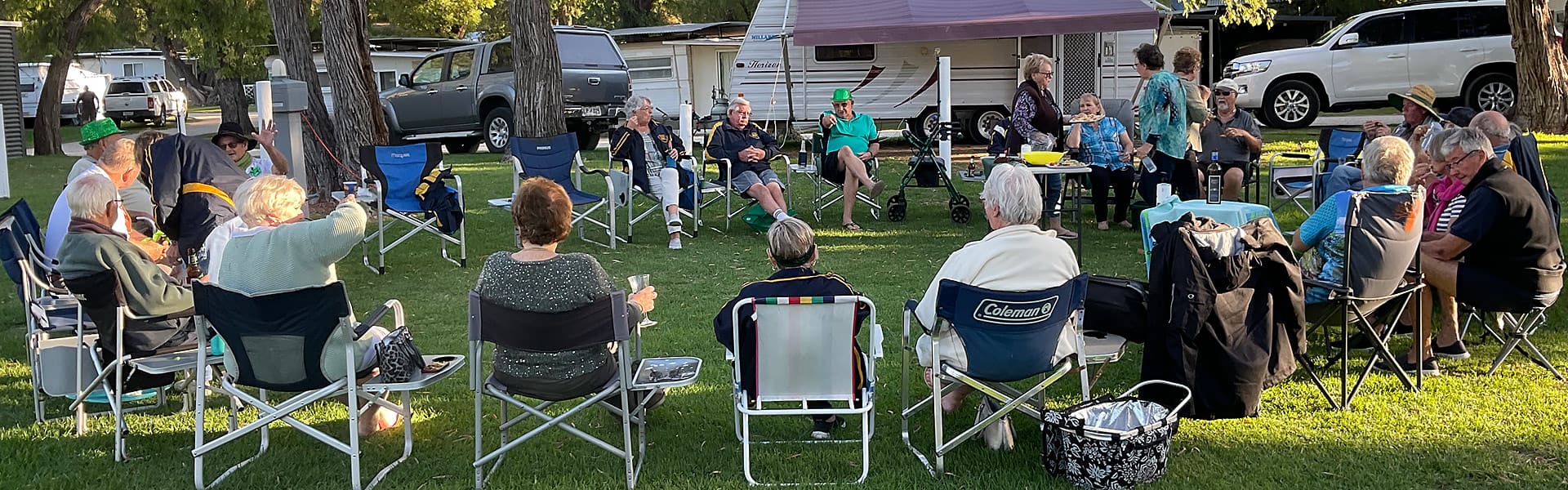 A group of caravanners sitting in a circle socialising in a caravan park