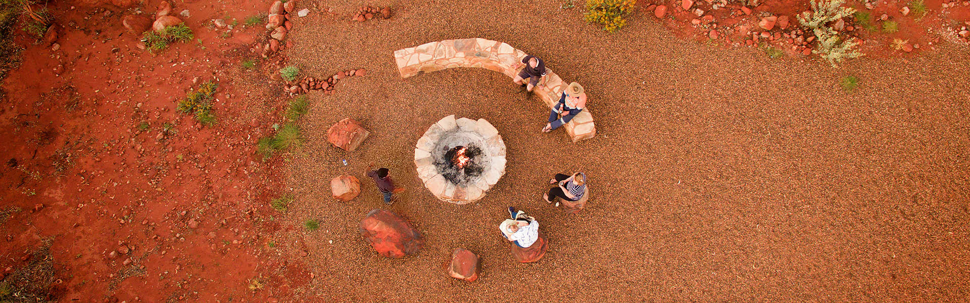 Aerial view of a group of people sitting in a circle around a campfire