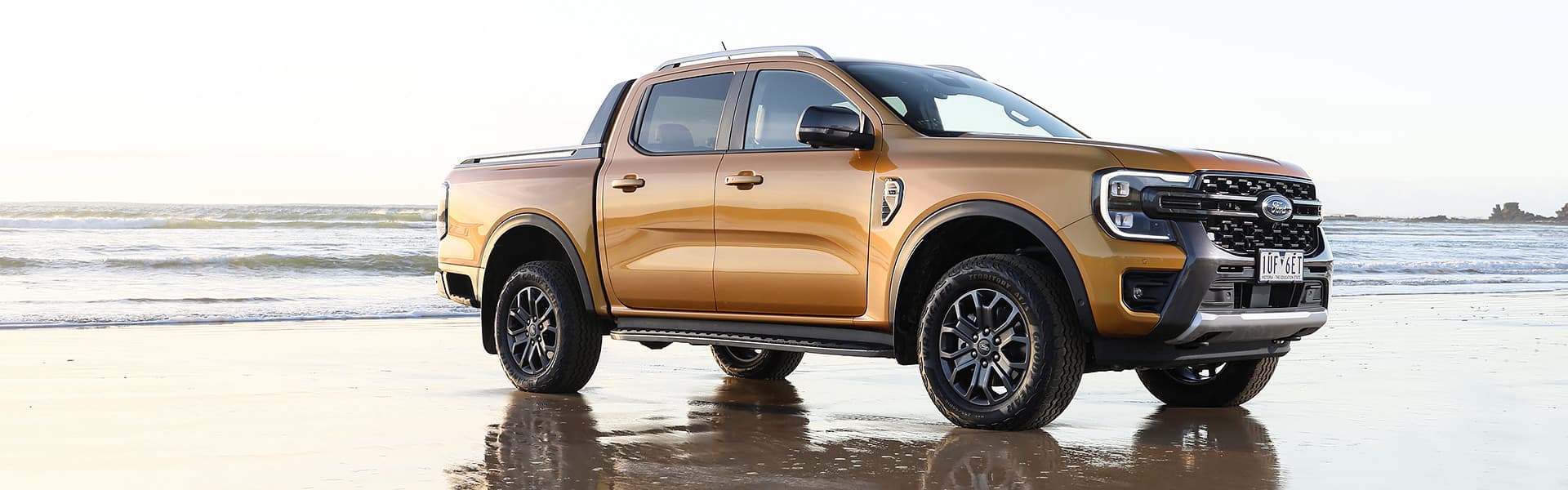 A gold Ford Ranger parked on a beach