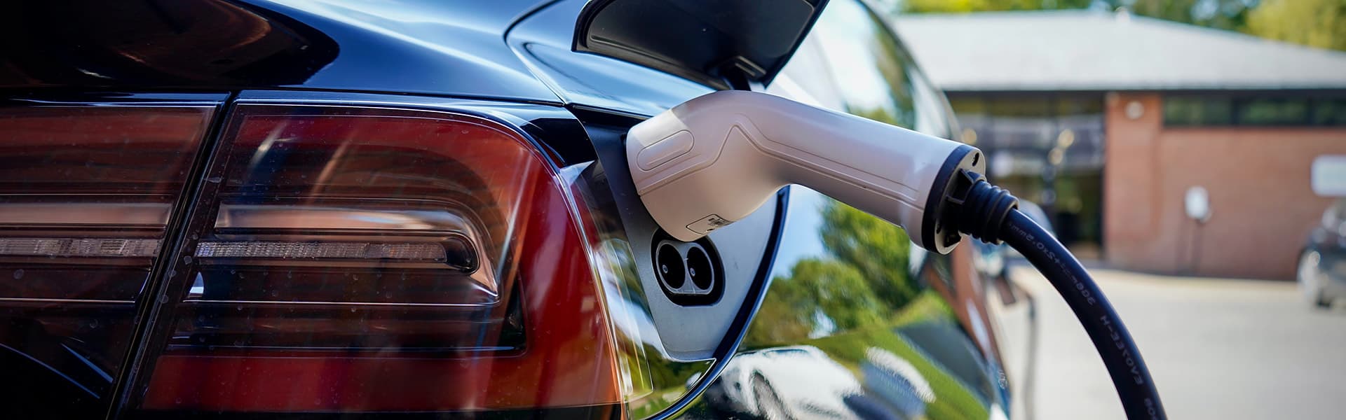 A black electric car being charged outside a home
