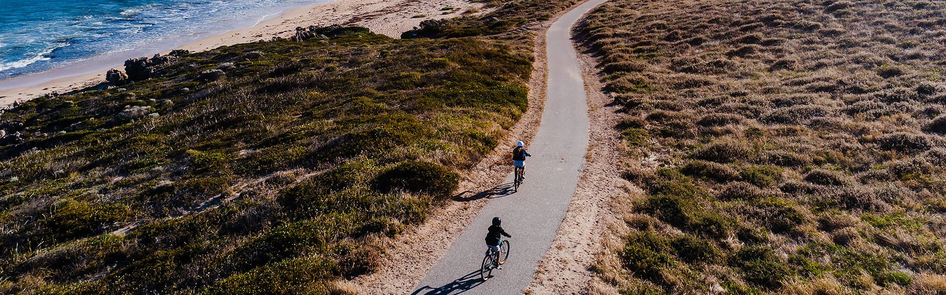 An aerial view of two children on a coastal bike path