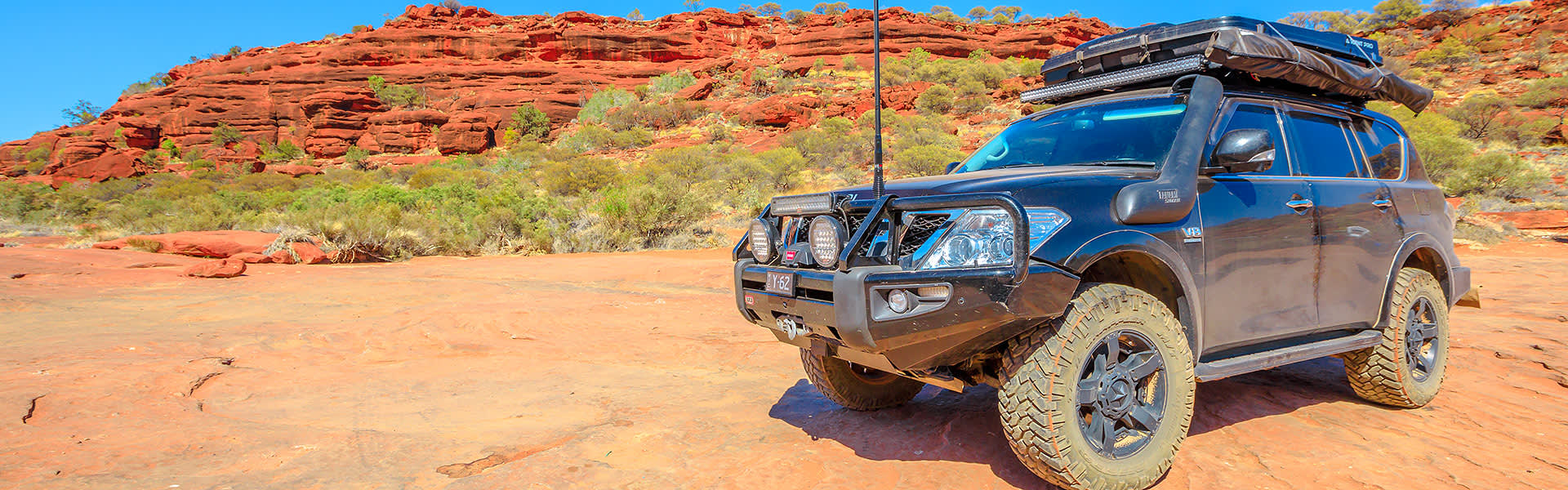 A four-wheel drive on a red dirt road