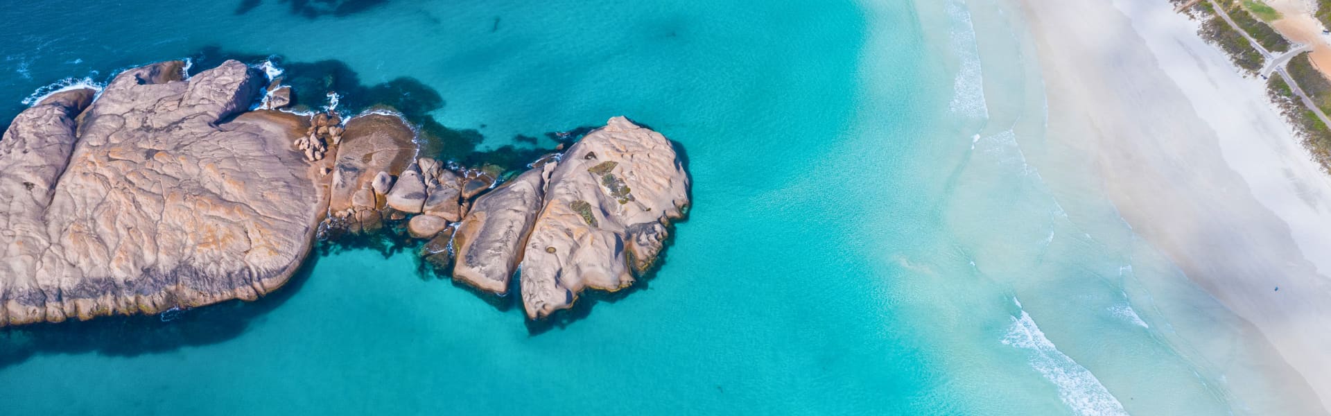 Aerial view of turquoise beach with mainland and rock formations in water