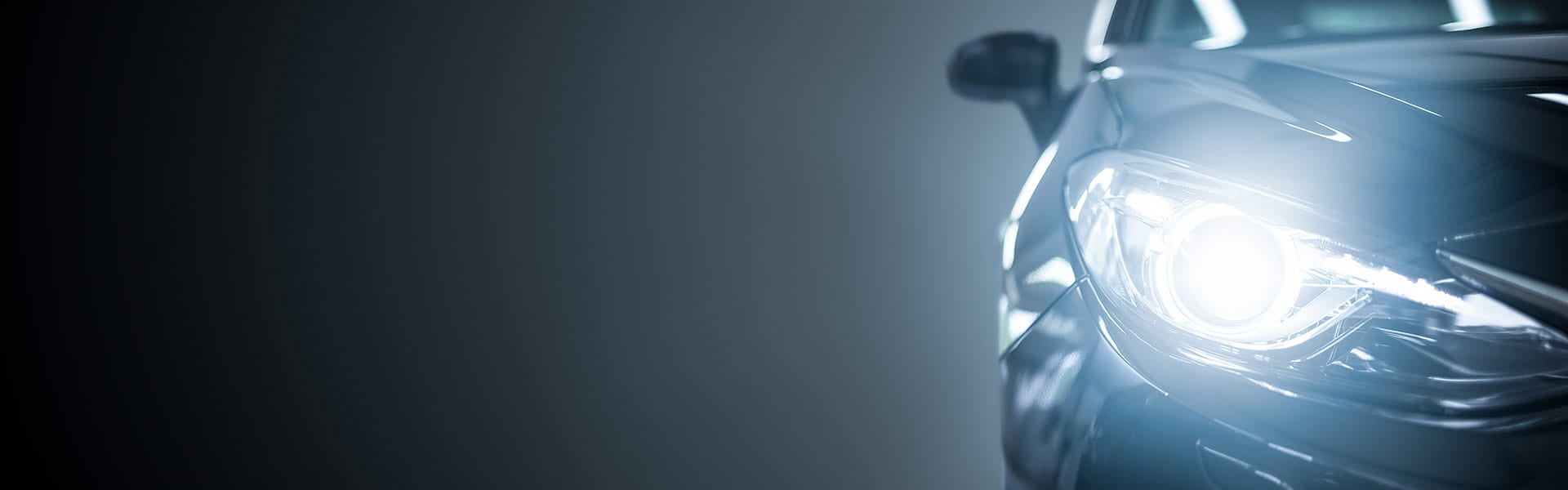 A single car headlight seen against a dark background